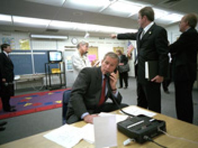 Director of Communications Dan Bartlett points to news footage of the World Trade Center Towers burning, September 11, 2001, as President George W. Bush gathers information about the attack while still at the Emma E. Booker Elementary School in Sarasota, Florida. (P7058-20A)