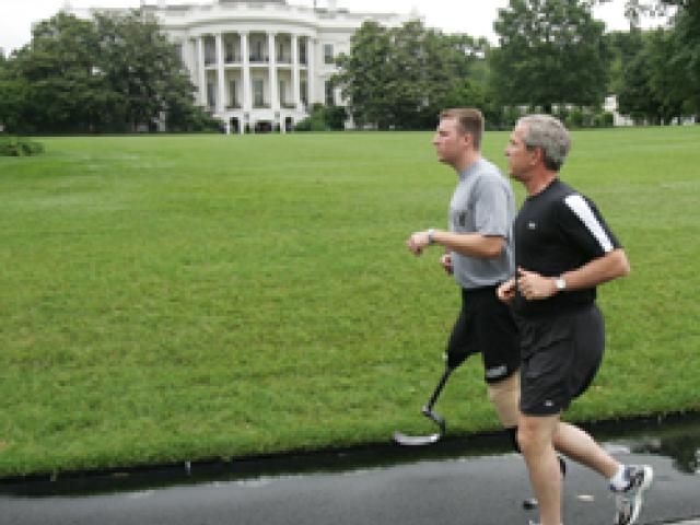 President George W. Bush runs with U.S. Army Staff Sergeant Christian Bagge of Eugene, Oregon, on the South Lawn, June 27, 2006. (P062706ED-0139)
