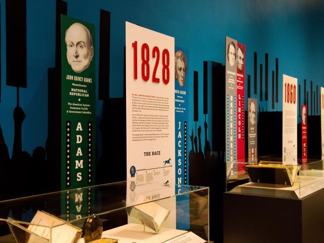 A photo of campaign memorabilia displays, with John Quincy Adams in the forefront, part of the 2016 Path to the Presidency exhibit at the George W Bush Library and Museum