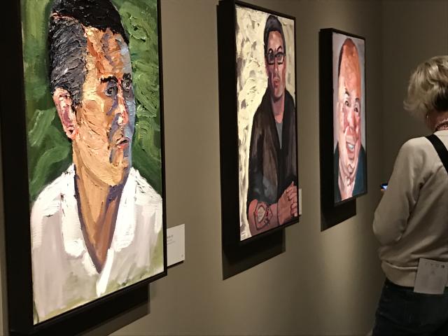 A photo of a visitor looking at three portraits in the 2017 exhibit Portraits of Courage, at the George W Bush Library and Museum