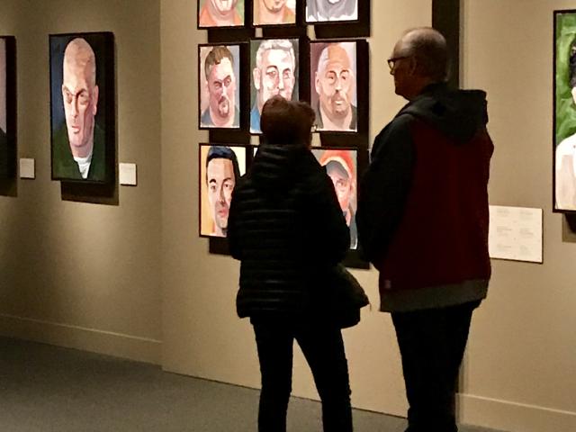 A photo of two visitors looking at a wall of portraits painted by President George W Bush, part of the 2017 exhibit Portraits of Courage, at the George W Bush Library and Museum 