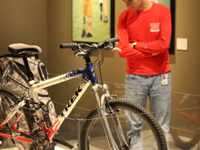 Photo of a visitor looking at the trek bicycle and golf back from the Portraits of Courage exhibit at the George W Bush Library and Museum