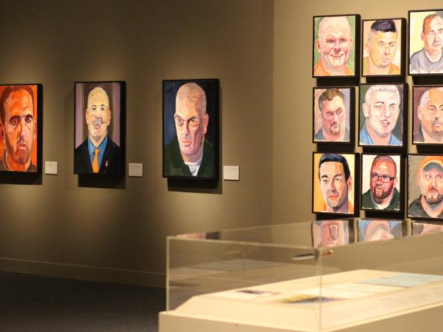 A photo of portraits hanging on the walls near an exhibit, part of the 2017 Portraits of Courage exhibit at the George W Bush Museum.