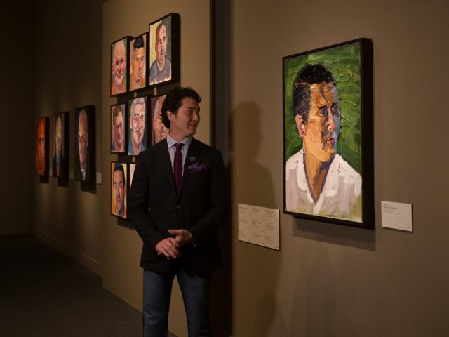 A photo of a man looking at his portrait painted by President George W Bush, part of the 2017 exhibit Portraits of Courage, at the George W Bush Library and Museum