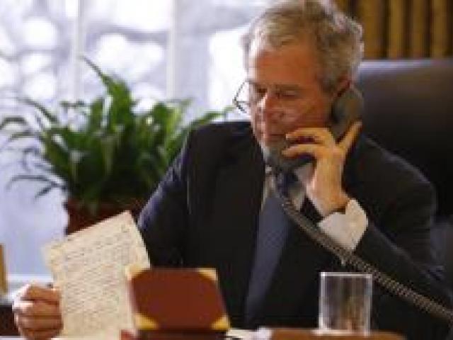 President George W. Bush reads a handwritten document while making telephone calls to world leaders in the Oval Office on January 19, 2009.