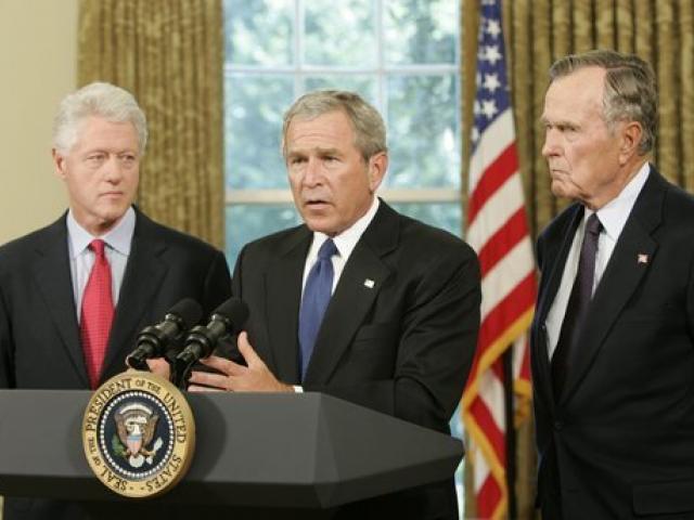 Standing with former Presidents Bill Clinton and George H. W. Bush, President George W. Bush discusses the plans to help people affected by Hurricane Katrina in the Oval Office Sept. 1, 2005.