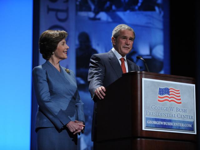 Woman and man standing in front of mic and podium