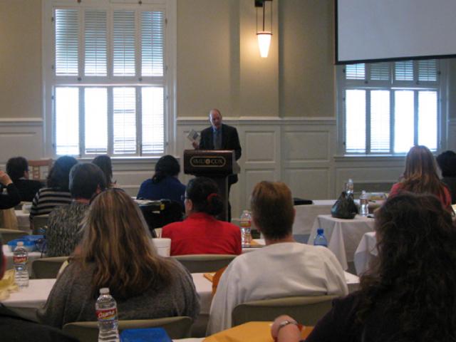 John Riley speaks at a podium in front of teachers