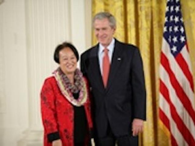 President George W. Bush welcomes Linda Uehara of Mililani, Hawaii, to the stage in the East Room of the White House, to receive the President’s Volunteer Service Award on May 10, 2007 